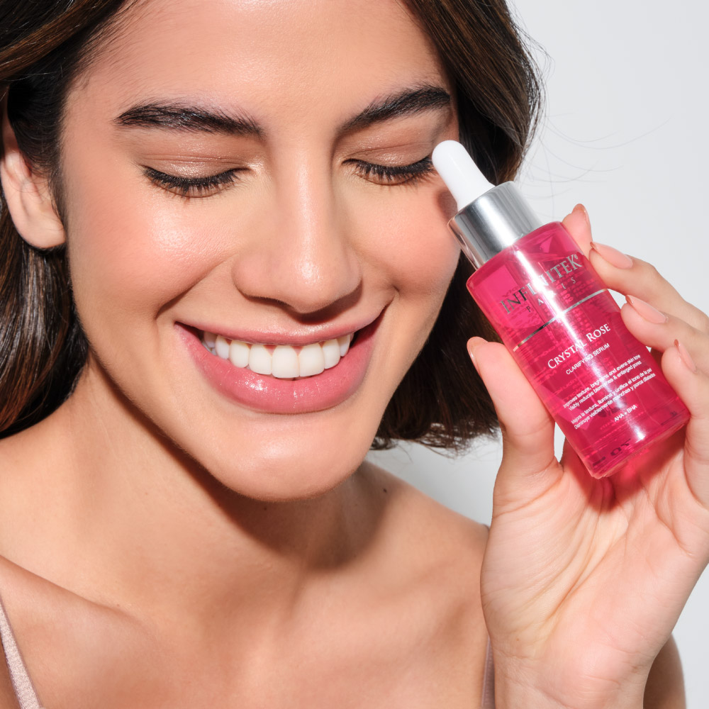 mujer latina sonriente con piel hermosa sosteniendo crystal rose serum de infinitek paris